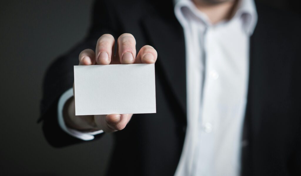 pexels-photo-326576-326576 A man in a suit presenting a blank business card for corporate usage.